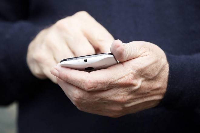 Eric Schmidt, executive chairman of Google, dials on the yet to be released Google produced Moto X phone at the annual Allen and Co. conference in Sun Valley